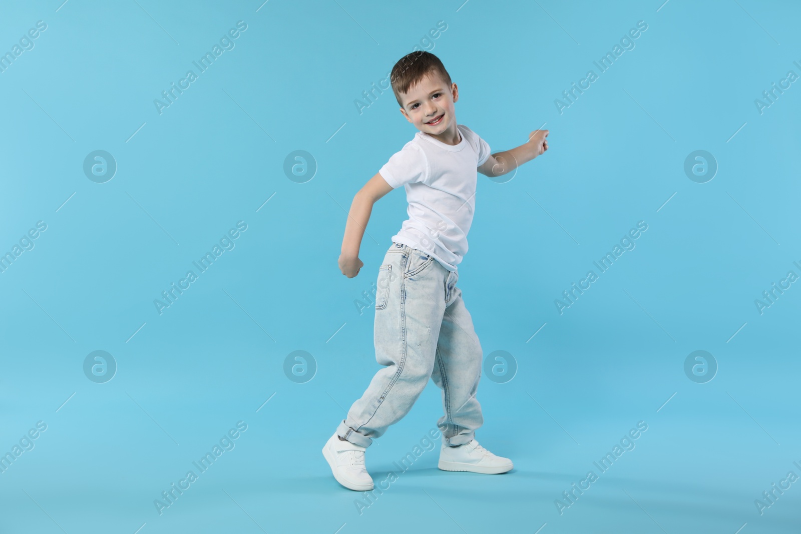 Happy little boy dancing on light blue background. Space for text Photo of Happy little boy dancing on light blue background. Space for text
