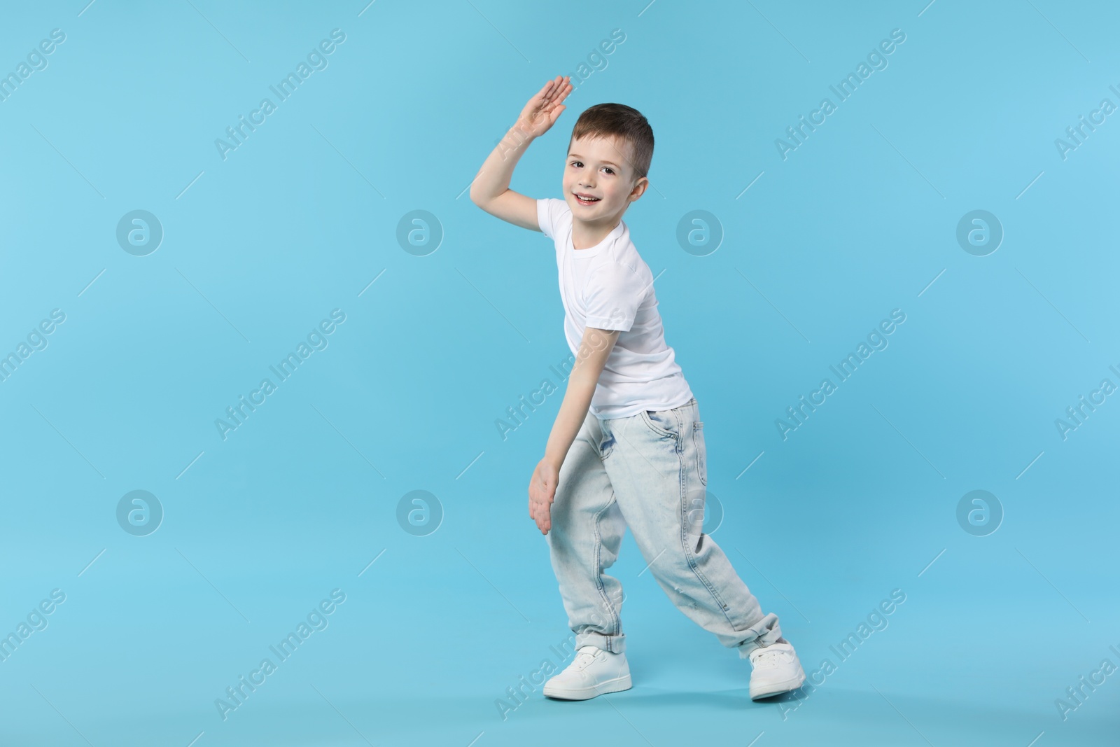 Happy little boy dancing on light blue background. Space for text Photo of Happy little boy dancing on light blue background. Space for text