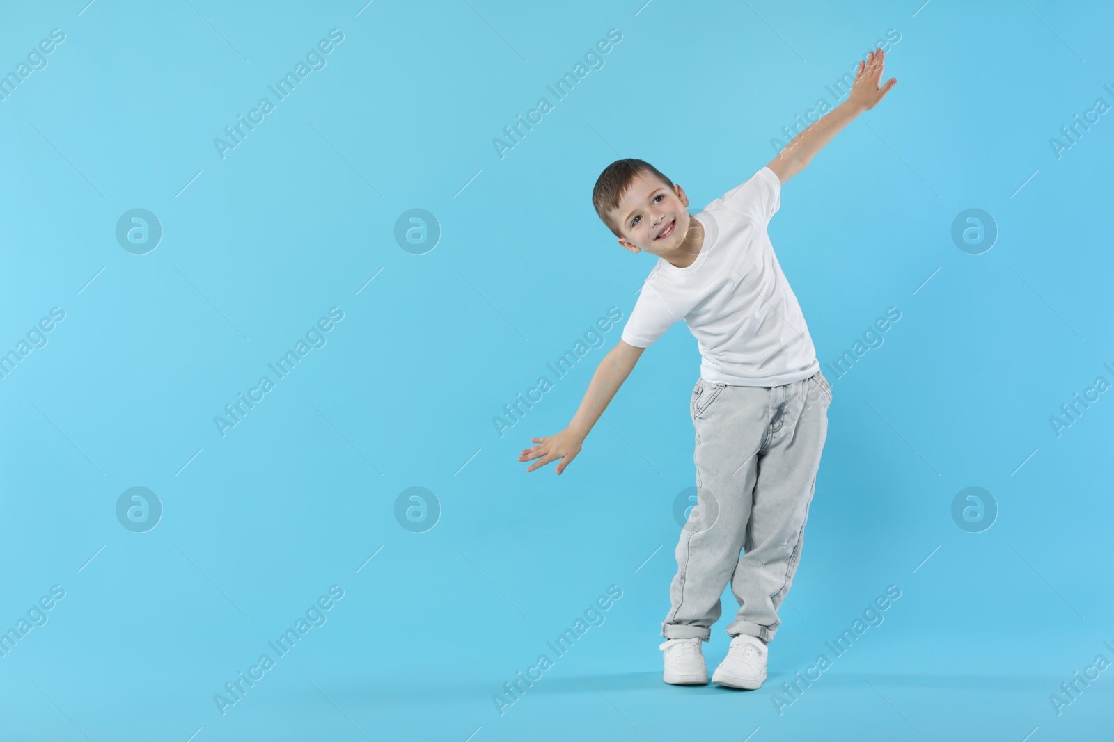 Happy little boy dancing on light blue background. Space for text Photo of Happy little boy dancing on light blue background. Space for text