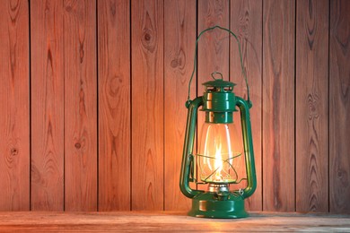 Photo of One vintage kerosene lantern on wooden table, space for text