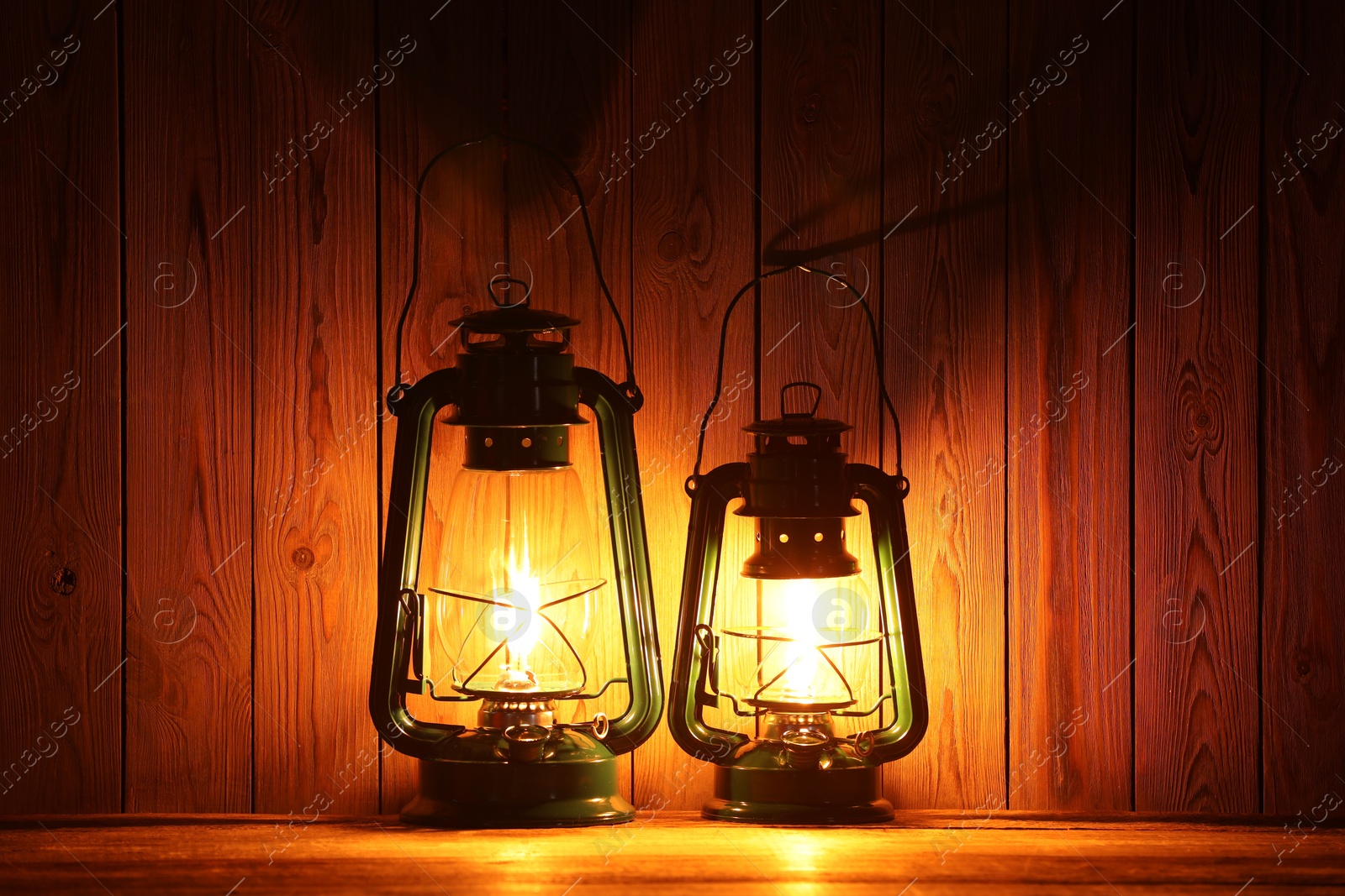 Two vintage kerosene lanterns on wooden table Photo of Two vintage kerosene lanterns on wooden table