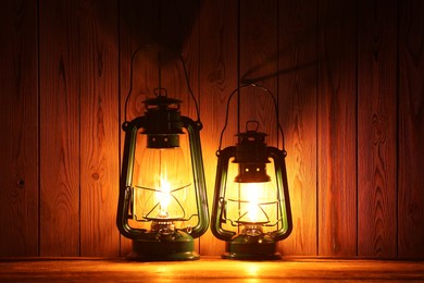 Photo of Two vintage kerosene lanterns on wooden table