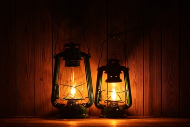 Photo of Two vintage kerosene lanterns on wooden table