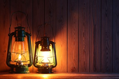 Photo of Vintage kerosene lanterns on wooden table, space for text