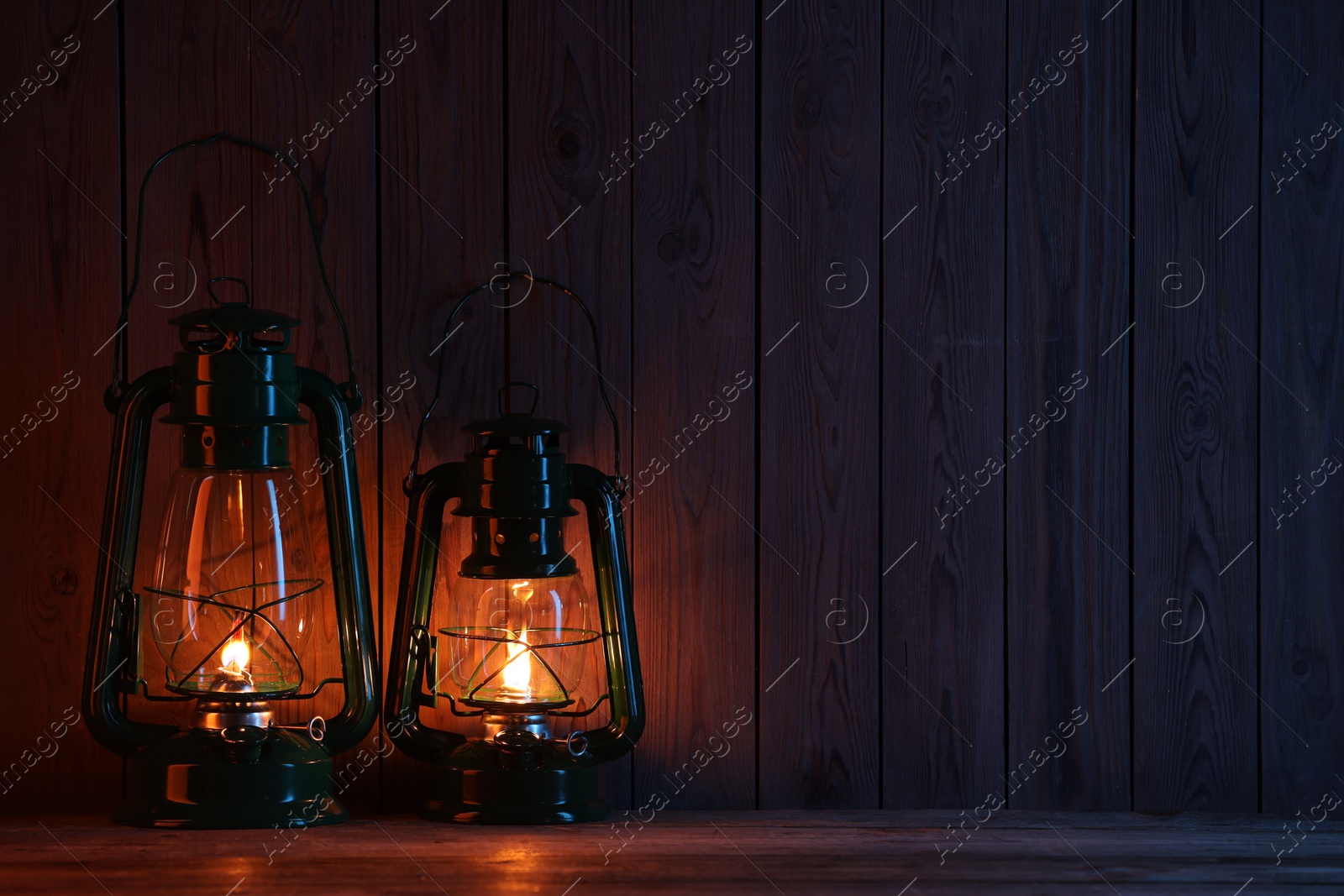 Vintage kerosene lanterns on wooden table, space for text Photo of Vintage kerosene lanterns on wooden table, space for text