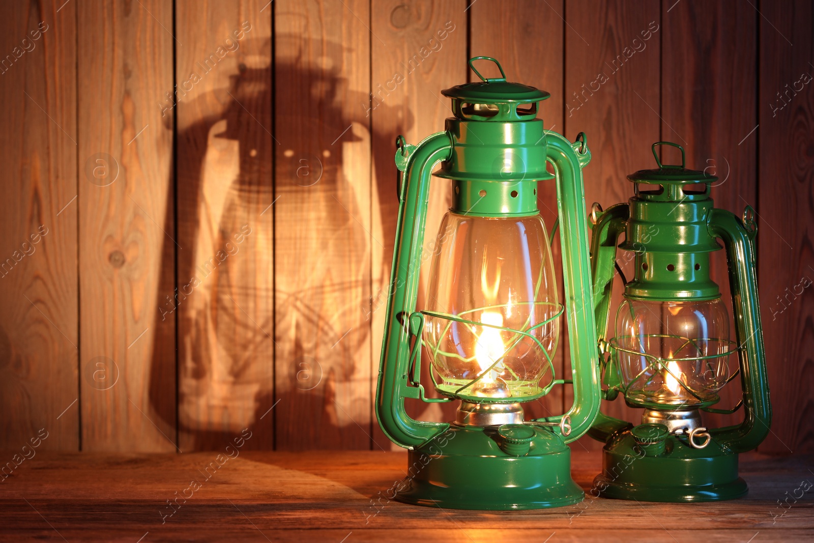 Photo of Vintage kerosene lanterns on wooden table, space for text