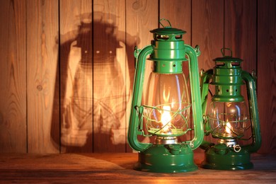 Photo of Vintage kerosene lanterns on wooden table, space for text