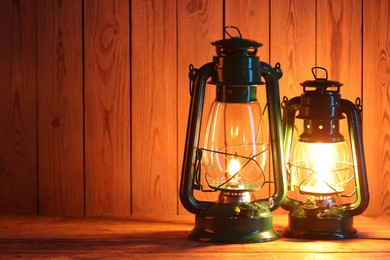 Photo of Vintage kerosene lanterns on wooden table, space for text