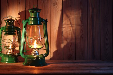 Photo of Vintage kerosene lanterns on wooden table, space for text