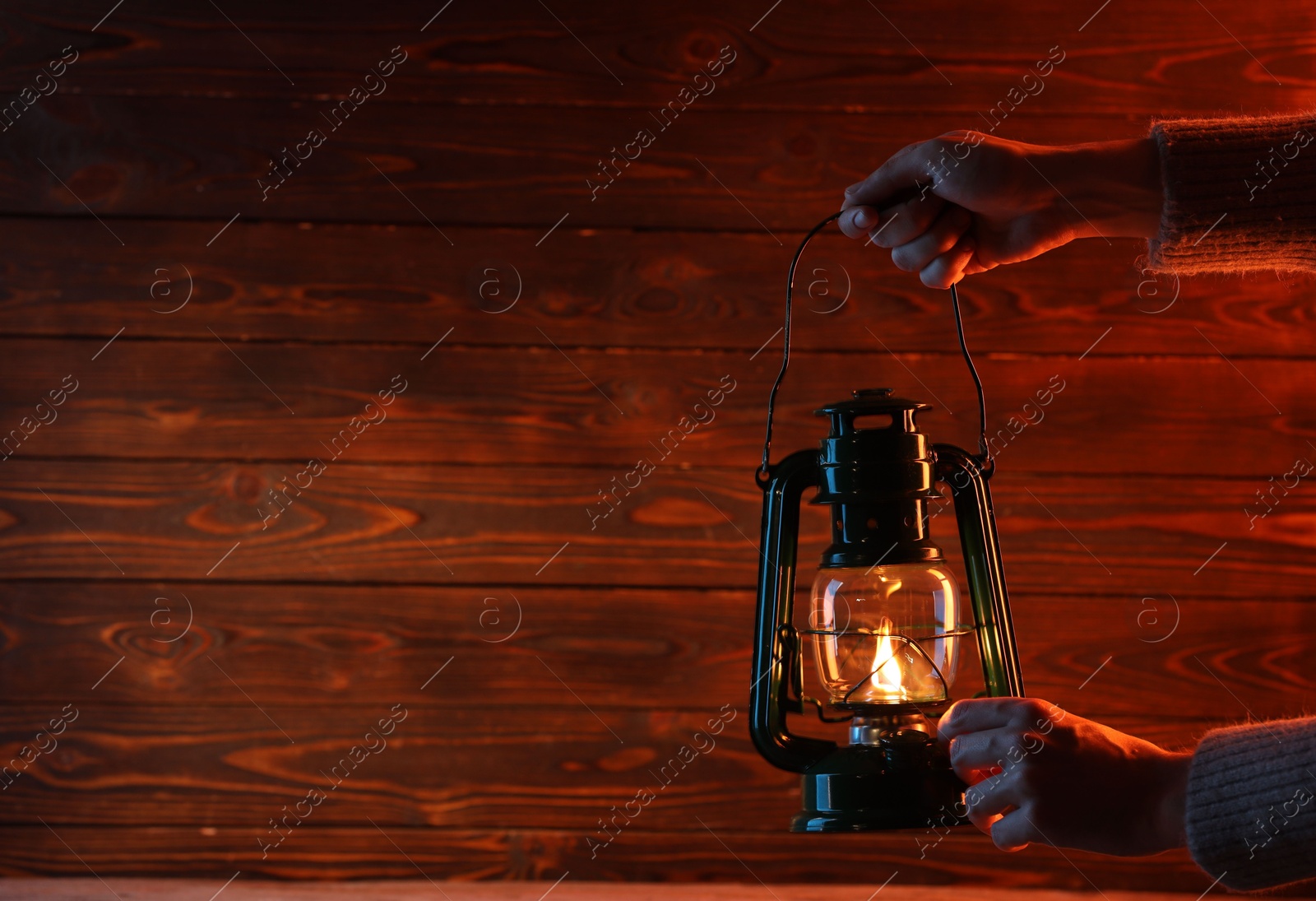 Woman holding vintage kerosene lantern near wooden wall, closeup. Space for text Photo of Woman holding vintage kerosene lantern near wooden wall, closeup. Space for text