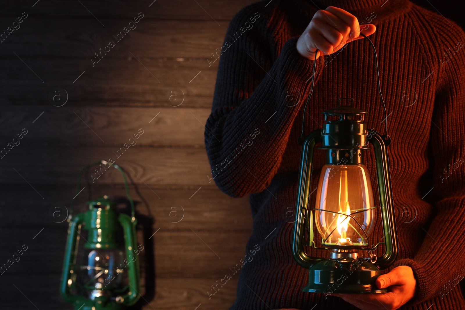 Man holding vintage kerosene lantern near wooden wall, closeup. Space for text Photo of Man holding vintage kerosene lantern near wooden wall, closeup. Space for text