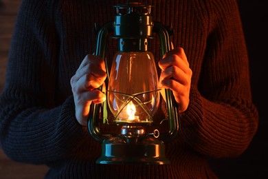 Photo of Man holding vintage kerosene lantern near wooden wall, closeup