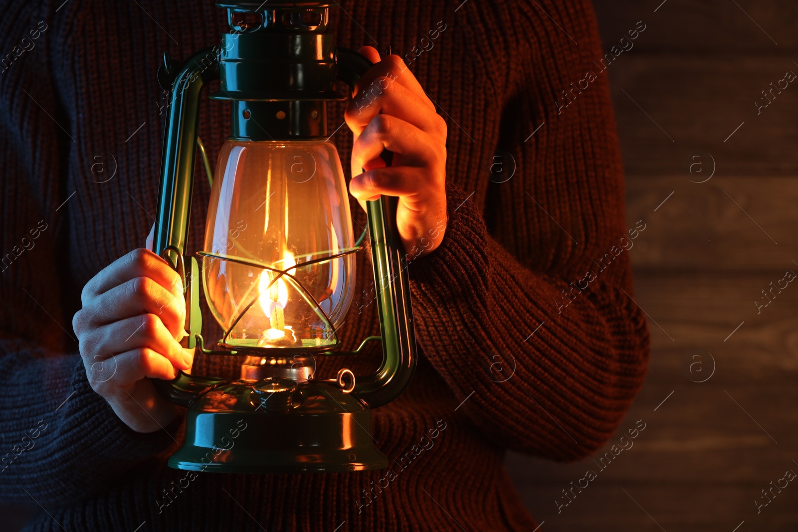 Man holding vintage kerosene lantern near wooden wall, closeup. Space for text Photo of Man holding vintage kerosene lantern near wooden wall, closeup. Space for text
