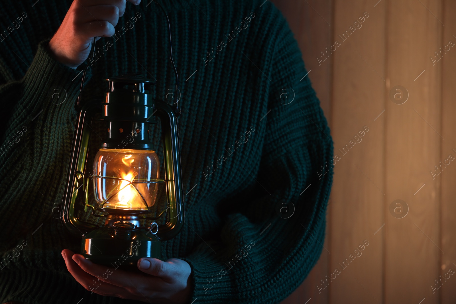Woman holding vintage kerosene lantern near wooden wall, closeup. Space for text Photo of Woman holding vintage kerosene lantern near wooden wall, closeup. Space for text
