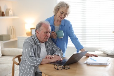Photo of Lovely senior couple watching something on laptop at table indoors