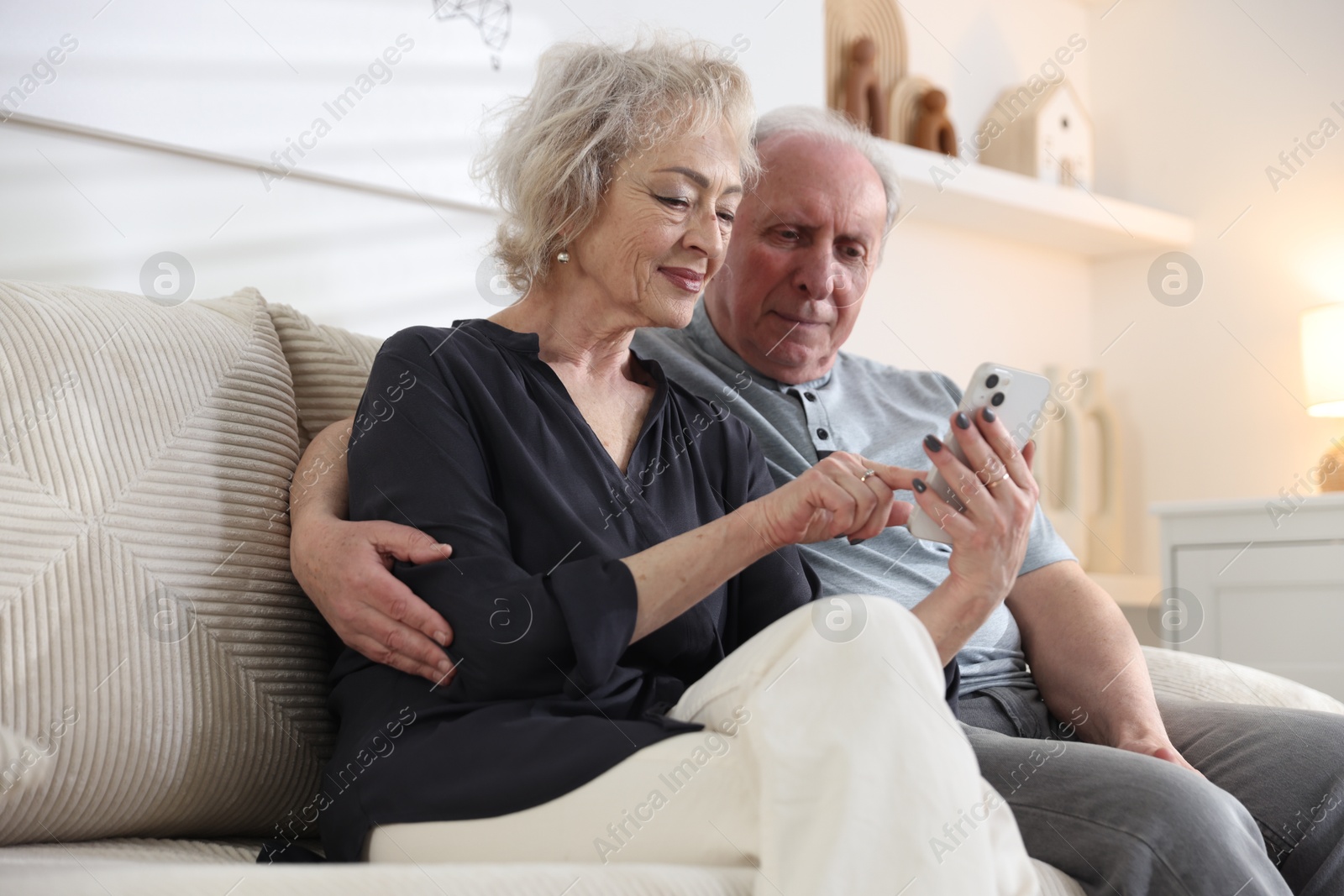 Photo of Lovely senior couple watching something on smartphone at home