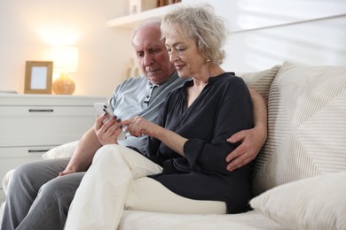 Photo of Lovely senior couple watching something on smartphone at home