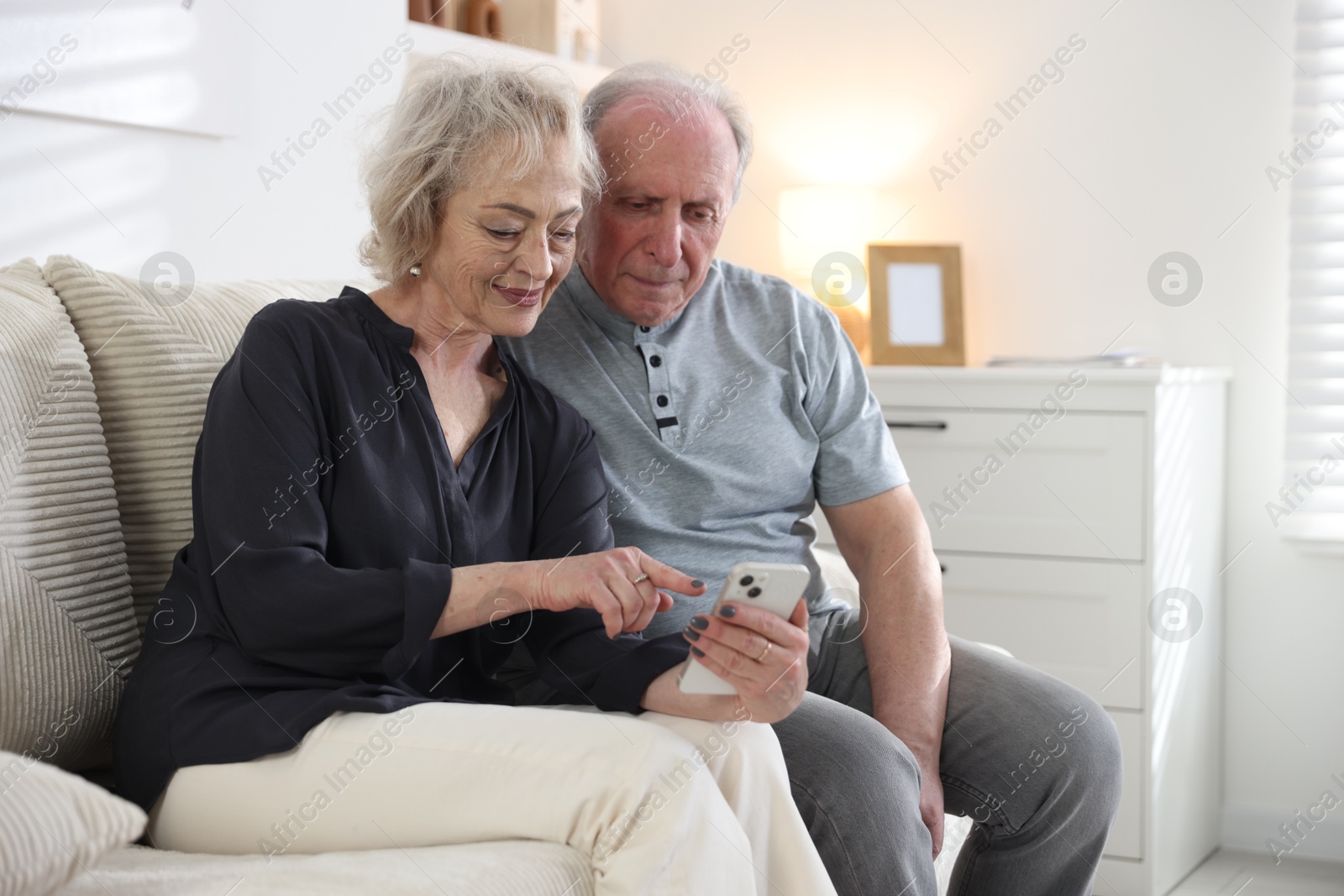 Lovely senior couple watching something on smartphone at home Photo of Lovely senior couple watching something on smartphone at home