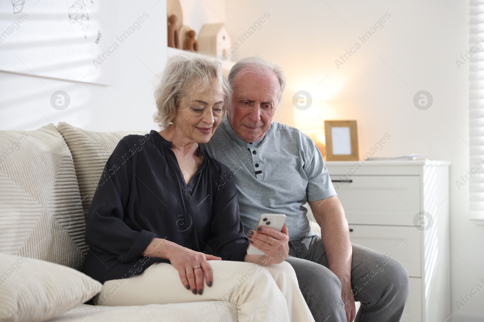 Lovely senior couple watching something on smartphone at home Photo of Lovely senior couple watching something on smartphone at home