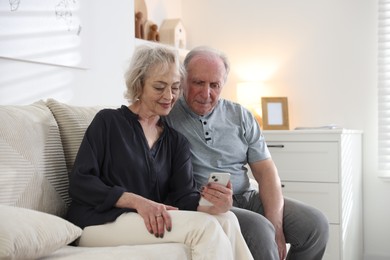 Photo of Lovely senior couple watching something on smartphone at home