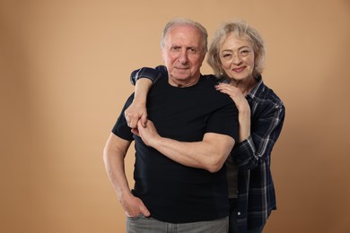 Photo of Portrait of lovely senior couple on beige background, space for text