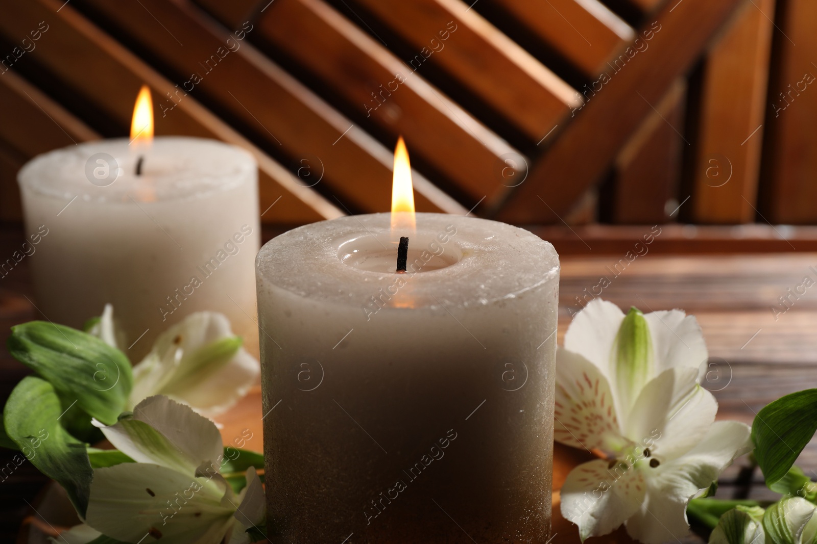 Burning candles and lily flowers on wooden table, closeup Photo of Burning candles and lily flowers on wooden table, closeup
