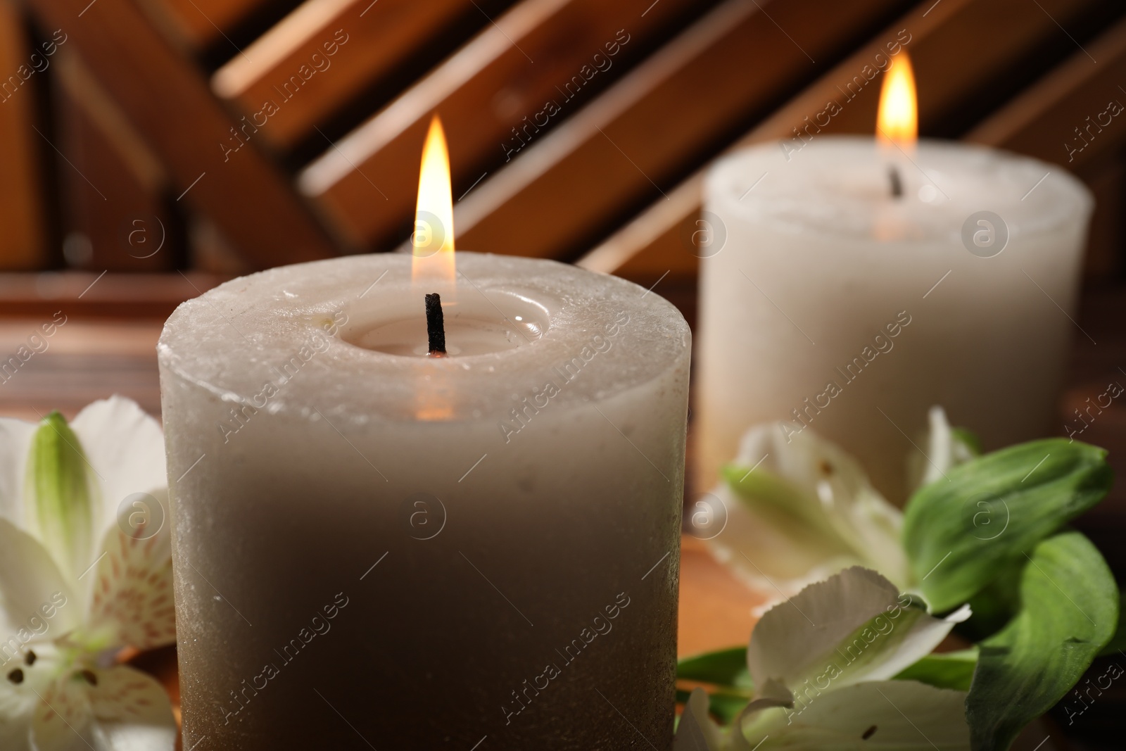Burning candles and lily flowers on wooden table, closeup Photo of Burning candles and lily flowers on wooden table, closeup