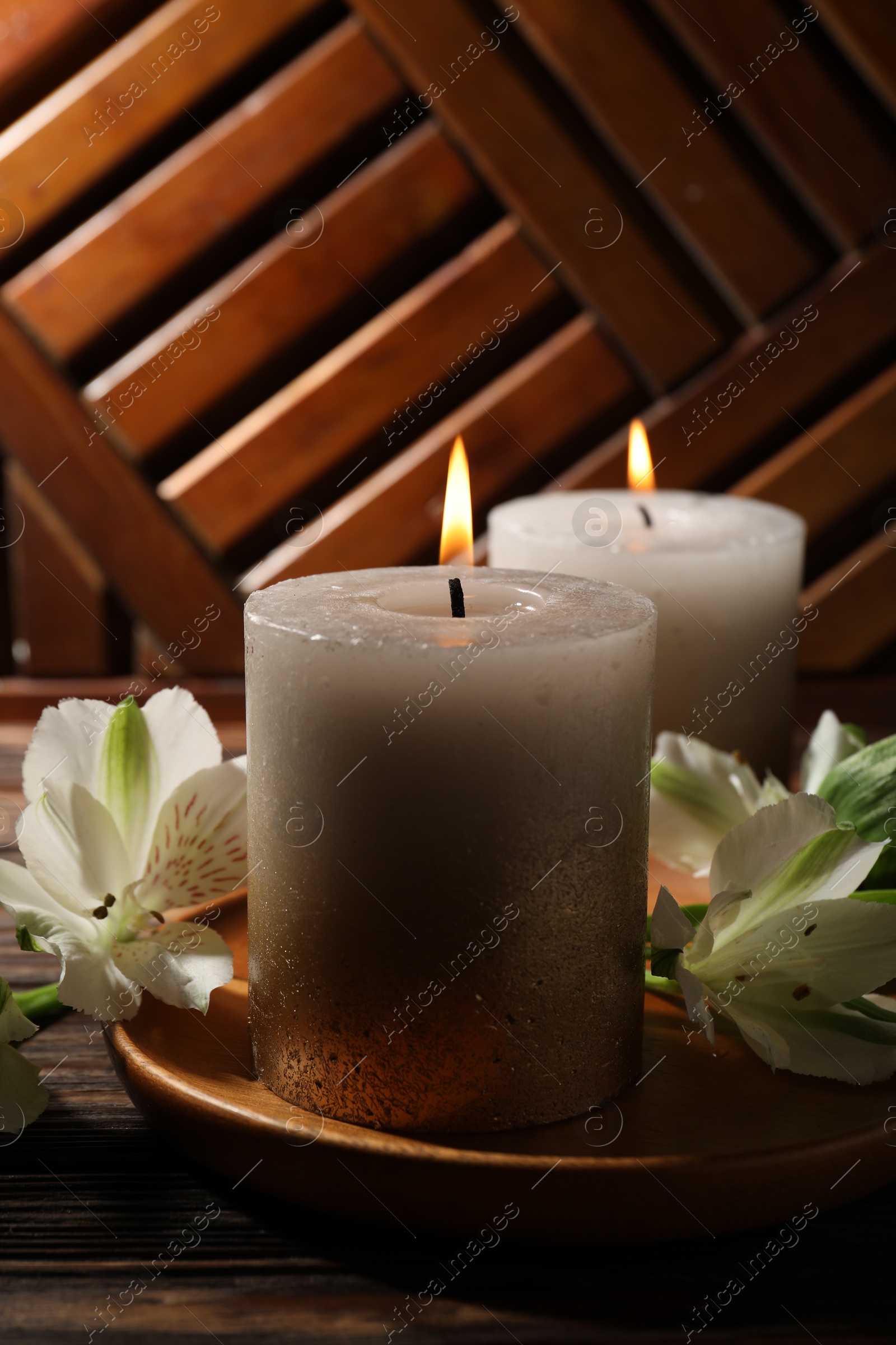 Burning candles and lily flowers on wooden table, closeup Photo of Burning candles and lily flowers on wooden table, closeup