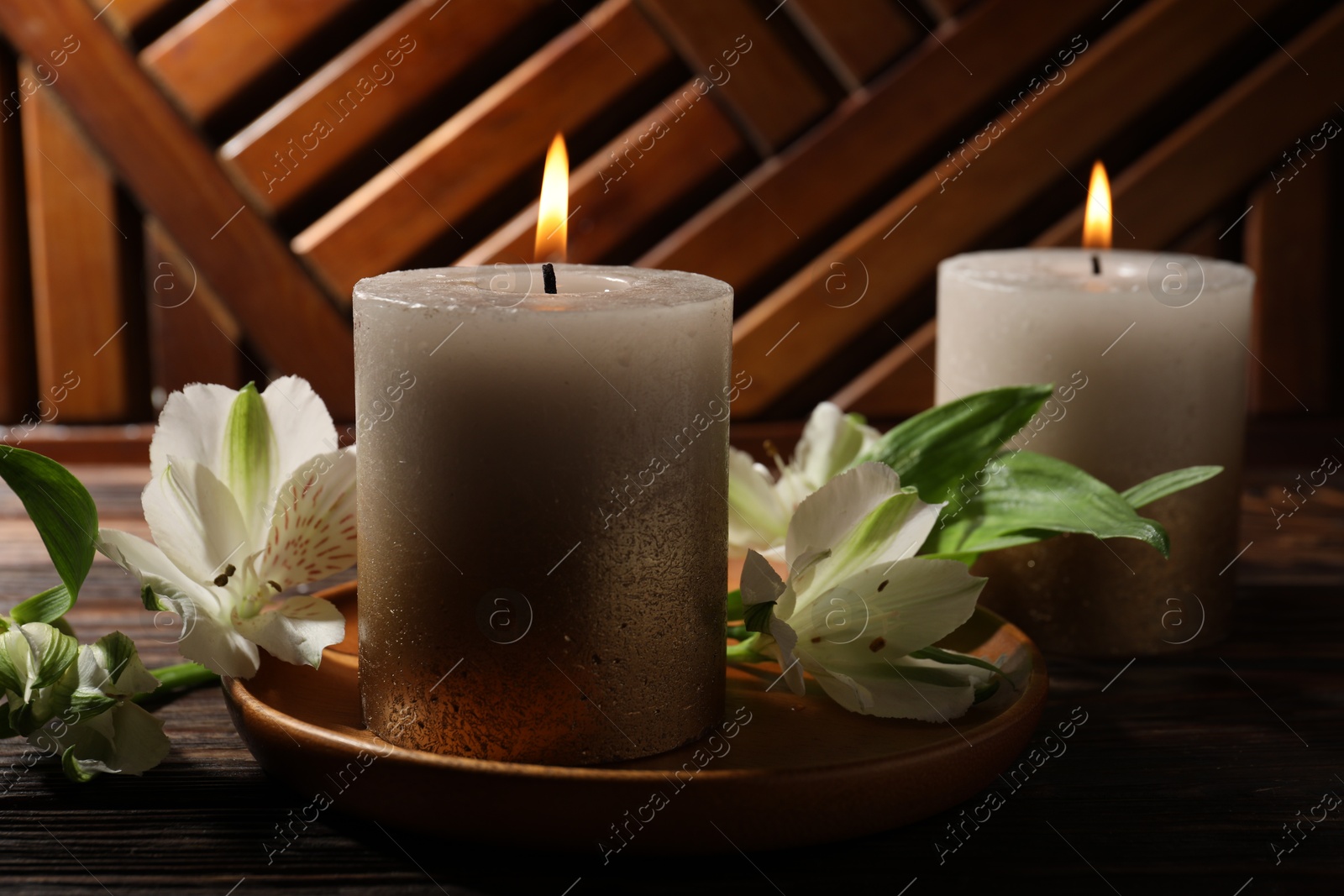 Burning candles and lily flowers on wooden table, closeup Photo of Burning candles and lily flowers on wooden table, closeup