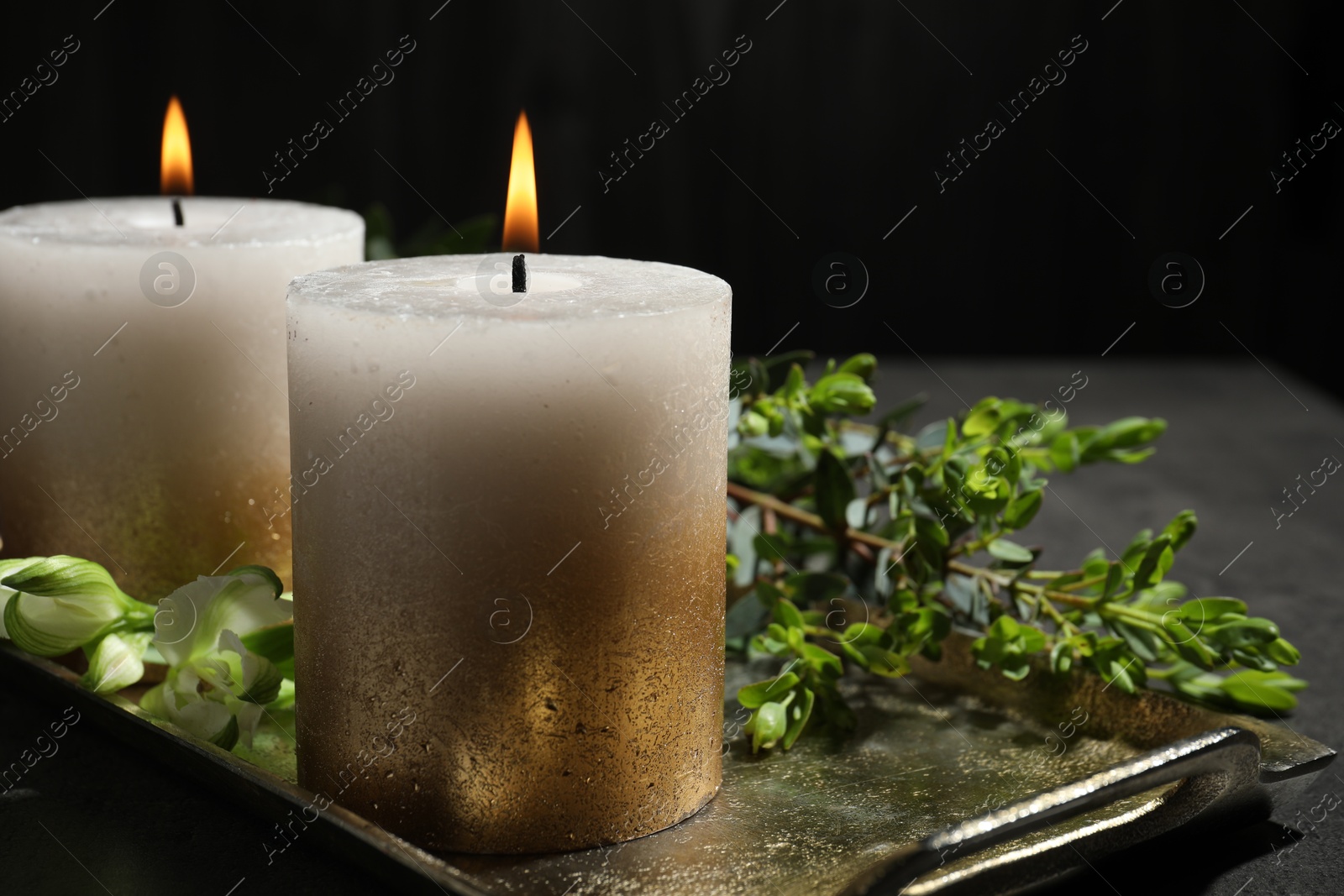 Burning candles and green leaves on black table, closeup Photo of Burning candles and green leaves on black table, closeup