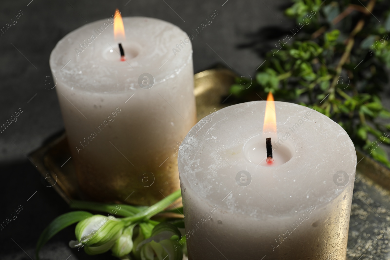 Burning candles and green leaves on black table, closeup Photo of Burning candles and green leaves on black table, closeup