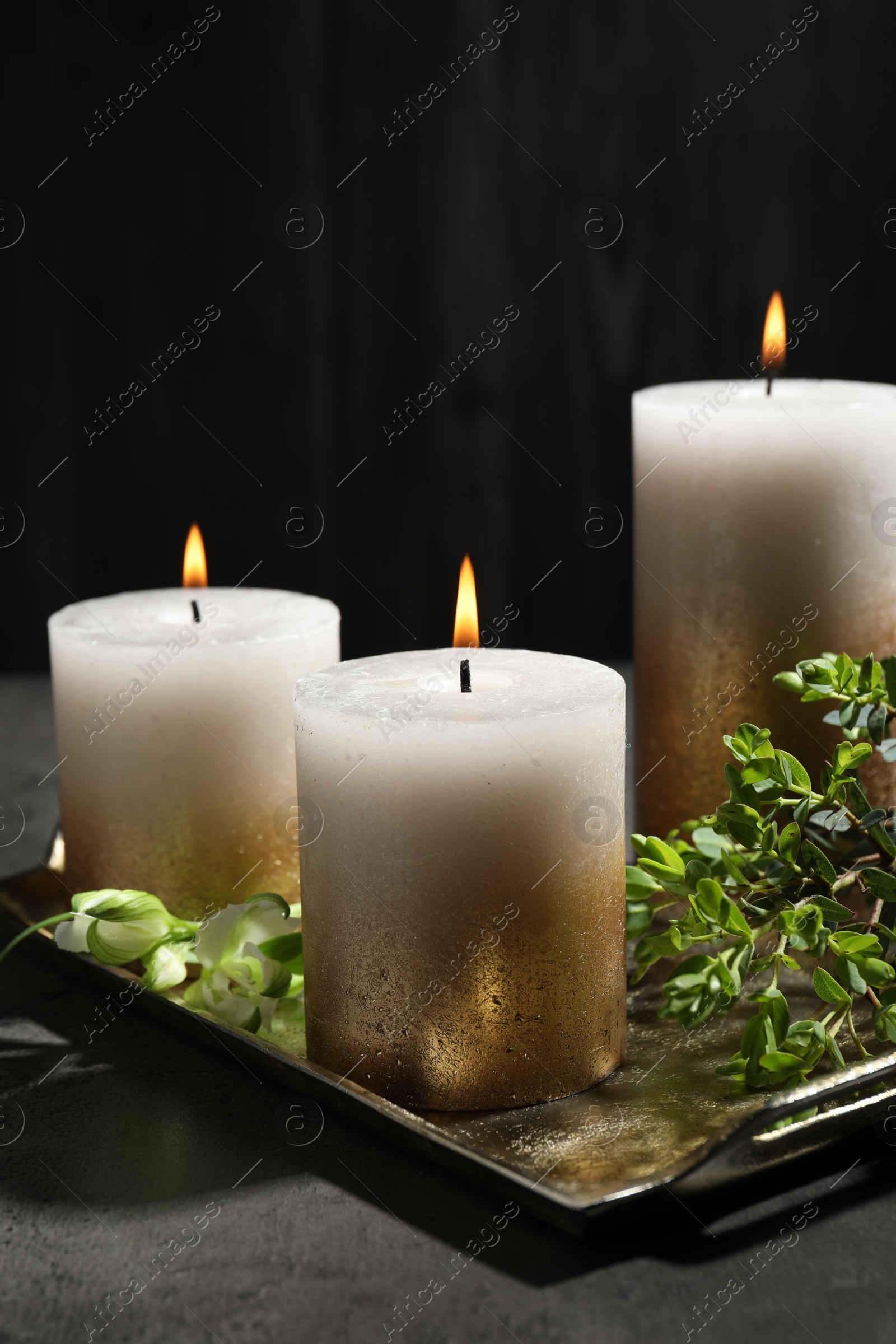 Burning candles and green leaves on black table, closeup Photo of Burning candles and green leaves on black table, closeup