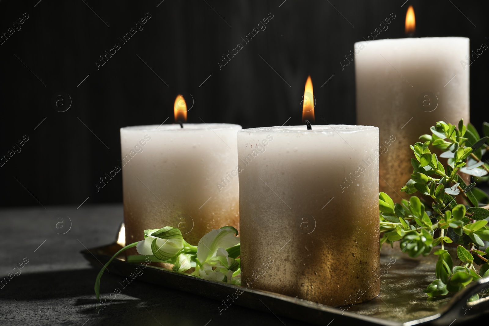 Burning candles and green leaves on black table, closeup Photo of Burning candles and green leaves on black table, closeup