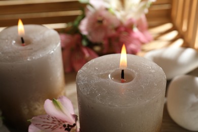 Photo of Burning candles, stones and lily flowers on table, closeup