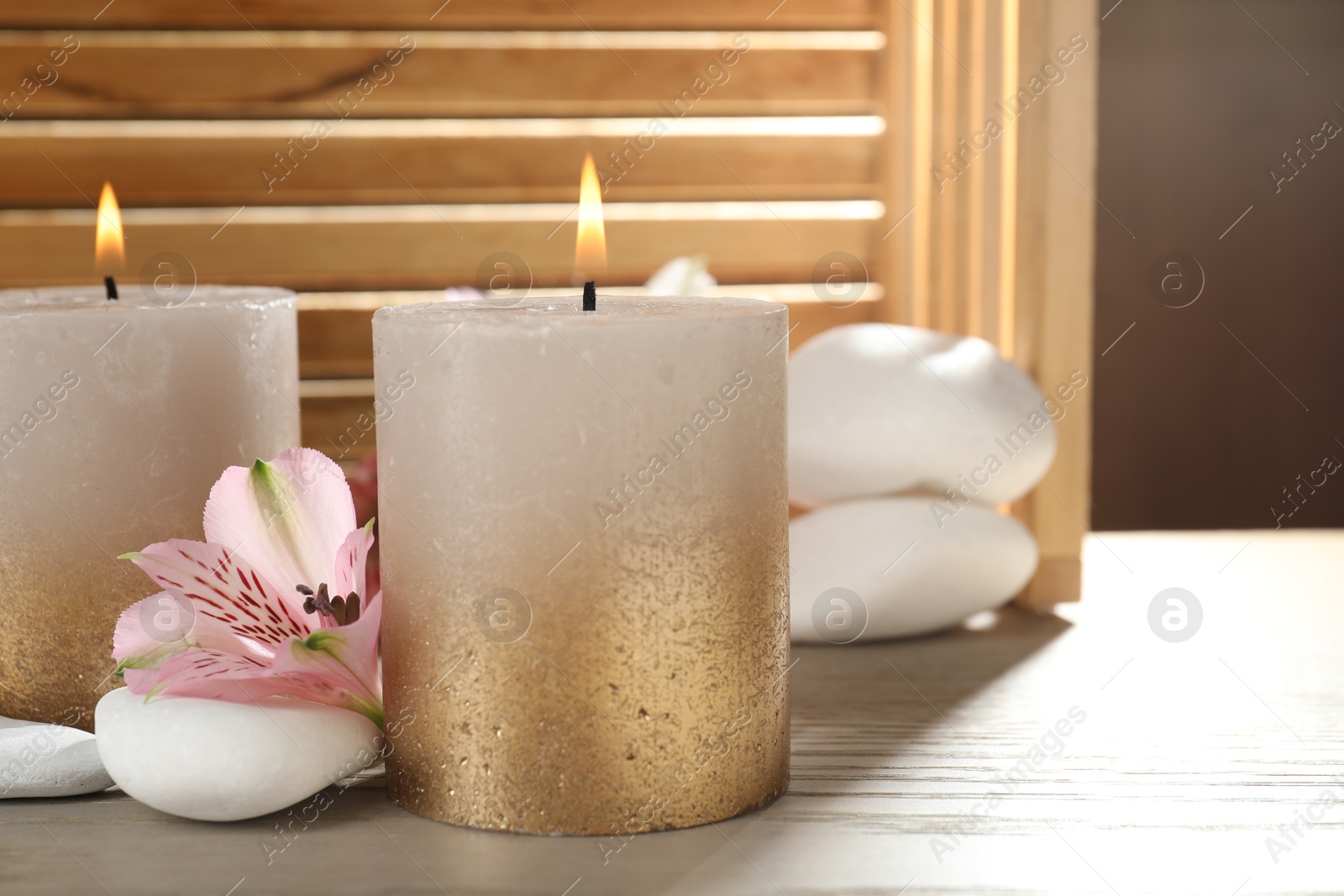 Burning candles, stones and lily flowers on wooden table, closeup Photo of Burning candles, stones and lily flowers on wooden table, closeup