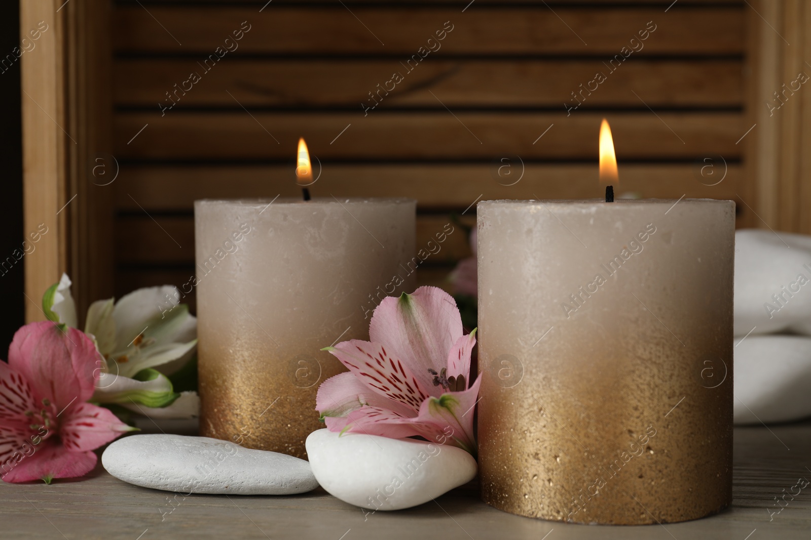 Burning candles, stones and lily flowers on wooden table, closeup Photo of Burning candles, stones and lily flowers on wooden table, closeup