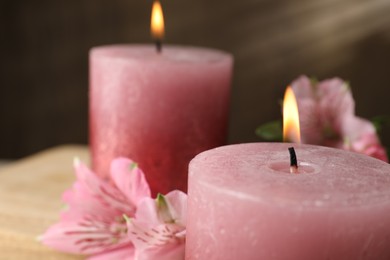 Photo of Burning candles and lily flowers on table, closeup