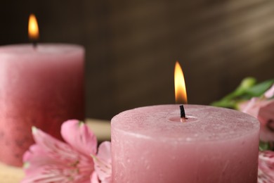 Photo of Burning candles and lily flowers on table, closeup