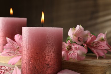 Photo of Burning candles and lily flowers on table, closeup