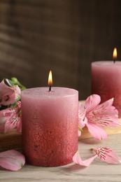 Photo of Burning candles and lily flowers on white wooden table, closeup