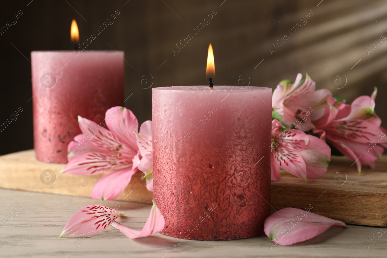Photo of Burning candles and lily flowers on white wooden table, closeup