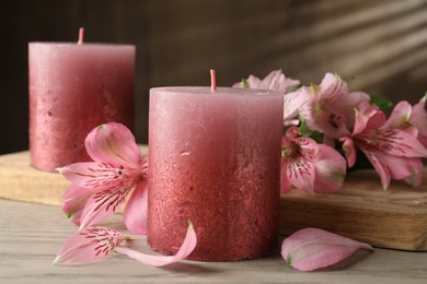Photo of Beautiful candles and lily flowers on white wooden table, closeup