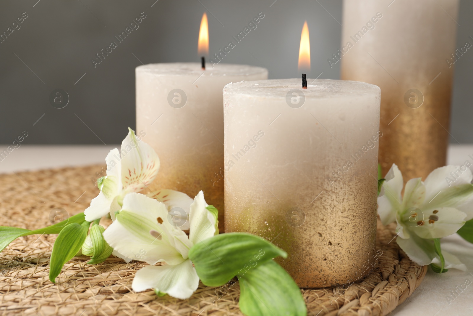 Burning candles and lily flowers on white table, closeup Photo of Burning candles and lily flowers on white table, closeup