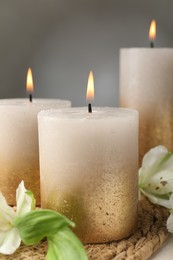 Photo of Burning candles and lily flowers on table, closeup