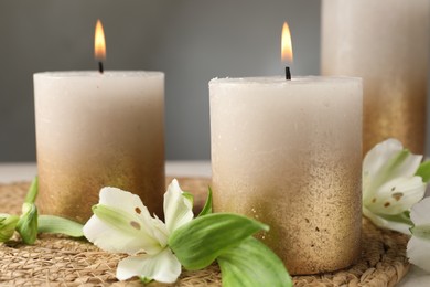 Photo of Burning candles and lily flowers on table, closeup