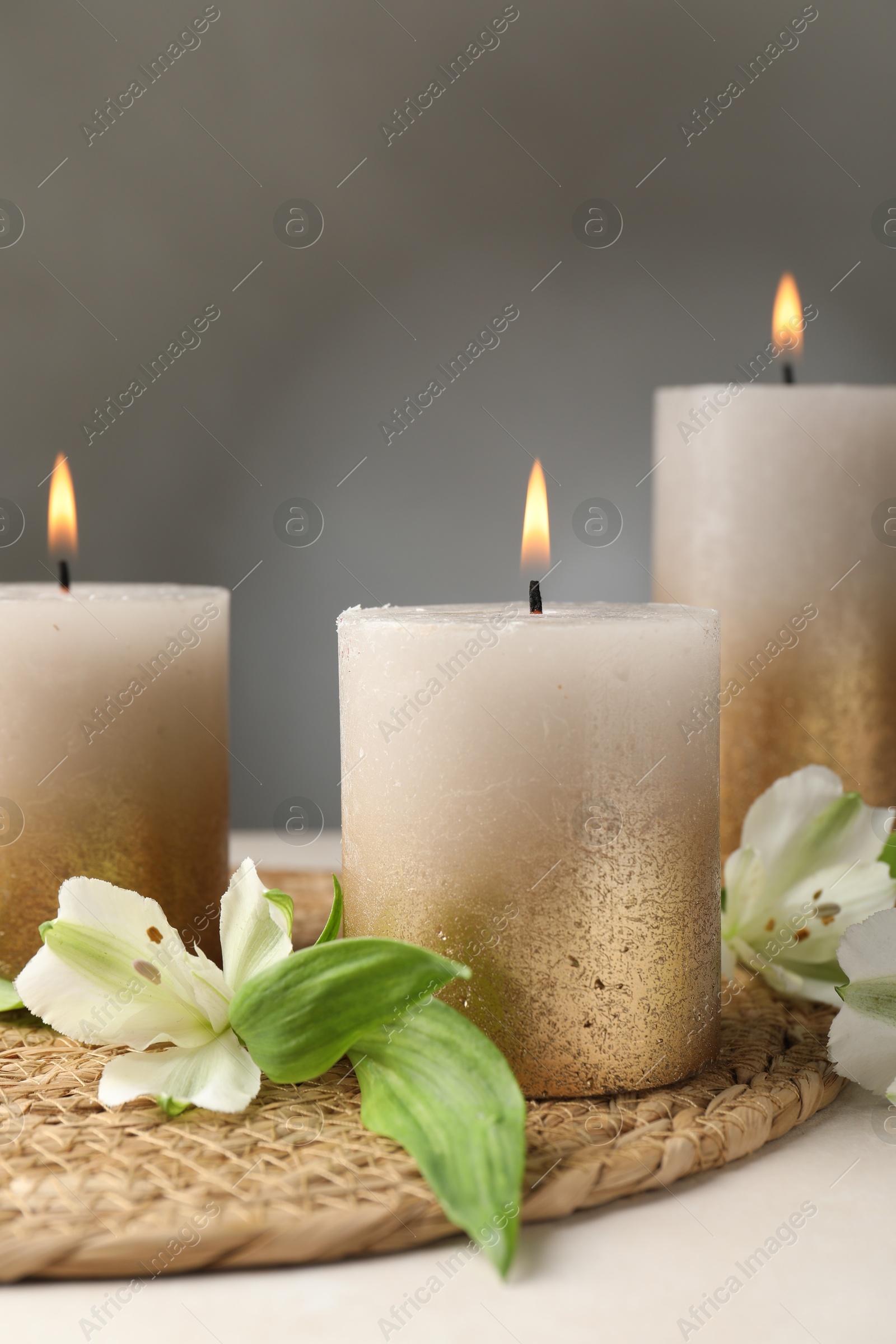 Burning candles and lily flowers on white table, closeup Photo of Burning candles and lily flowers on white table, closeup