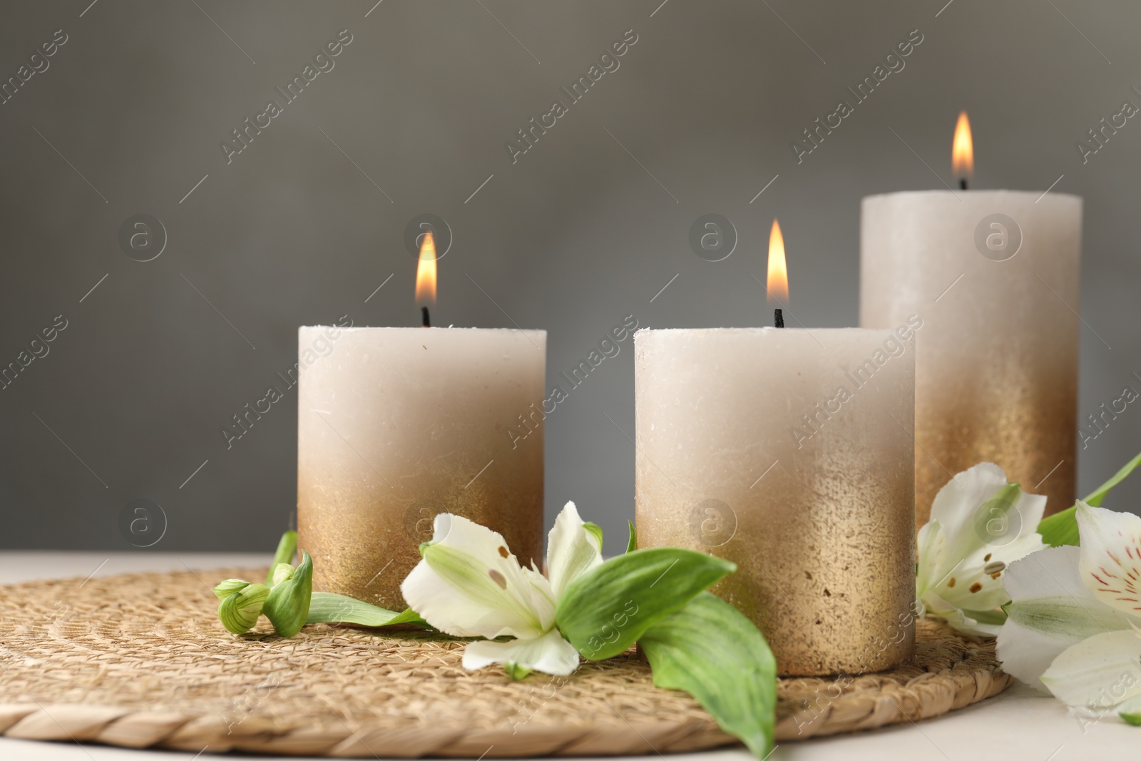 Burning candles and lily flowers on white table Photo of Burning candles and lily flowers on white table