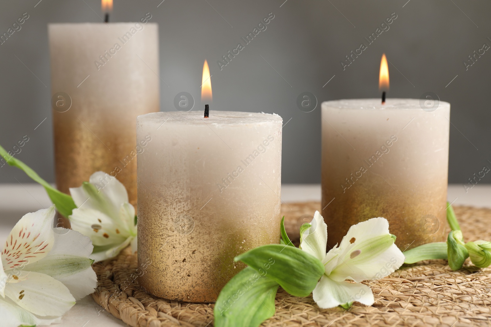 Burning candles and lily flowers on white table, closeup Photo of Burning candles and lily flowers on white table, closeup