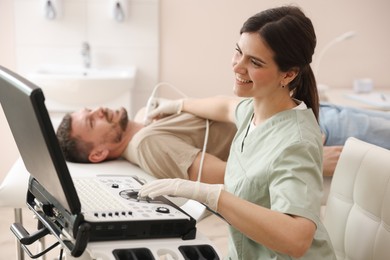 Photo of Sonographer conducting ultrasound examination of man's thyroid gland in clinic