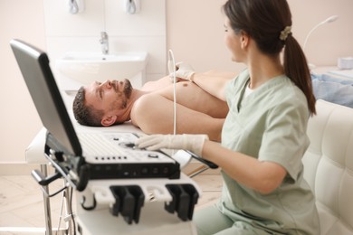 Photo of Sonographer conducting ultrasound examination of man's heart in clinic